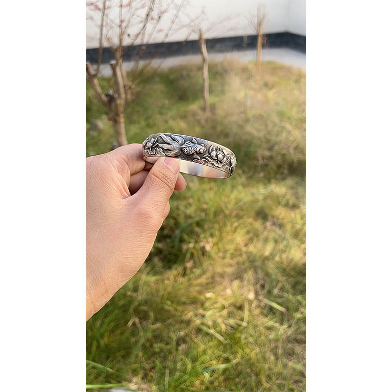 What processes are used to enhance the antique feel of the vintage fish and lotus sterling silver bangle?